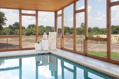 Photo of a large modern indoor rectangular pool in Austin with concrete slab.
