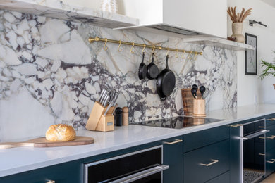 Large minimalist l-shaped light wood floor and brown floor kitchen pantry photo in Philadelphia with an undermount sink, flat-panel cabinets, green cabinets, quartz countertops, white backsplash, marble backsplash, paneled appliances, an island and white countertops