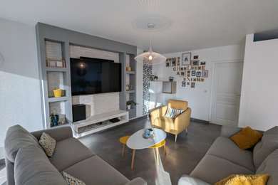 Cette image montre une salle de séjour nordique de taille moyenne avec un mur blanc, un téléviseur fixé au mur et un sol gris.