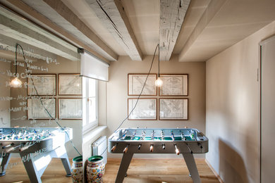 Photo of a small industrial loft-style family room in Other with beige walls, medium hardwood floors and a game room.