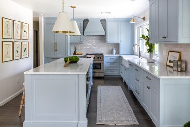 Example of a mid-sized classic l-shaped dark wood floor and brown floor eat-in kitchen design in Philadelphia with a farmhouse sink, shaker cabinets, blue cabinets, marble countertops, white backsplash, ceramic backsplash, paneled appliances, an island and white countertops