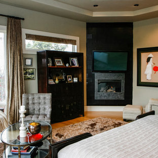Ispirazione per una grande camera matrimoniale etnica con pareti beige, pavimento in legno massello medio, camino ad angolo e cornice del camino piastrellata