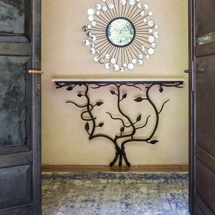 Idée de décoration pour un grand hall d'entrée bohème avec un mur jaune, un sol en bois clair, une porte double, une porte métallisée et un sol jaune.