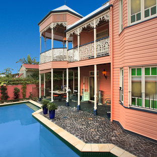 Foto på ett vintage rosa hus, med två våningar, valmat tak och tak i metall