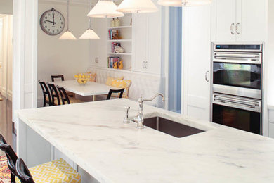 Enclosed kitchen - large transitional galley dark wood floor enclosed kitchen idea in New York with an undermount sink, raised-panel cabinets, white cabinets, marble countertops, white backsplash, stone tile backsplash, stainless steel appliances and an island