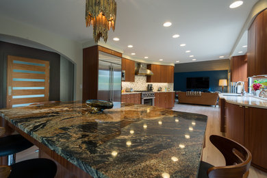 Large trendy light wood floor open concept kitchen photo in Boise with flat-panel cabinets, dark wood cabinets, granite countertops, beige backsplash, stone tile backsplash, paneled appliances and an island
