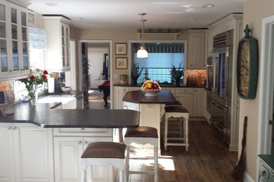 Example of a cement tile floor kitchen design in New York with a farmhouse sink, white cabinets, granite countertops, beige backsplash, ceramic backsplash, stainless steel appliances and two islands