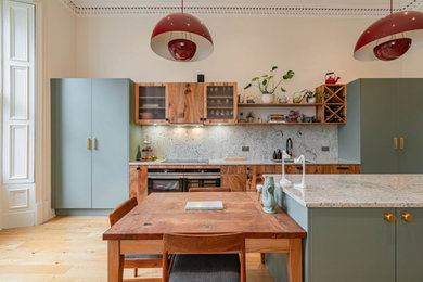 Inredning av ett rustikt stort vit vitt kök, med en integrerad diskho, släta luckor, gröna skåp, integrerade vitvaror, en köksö och brunt golv