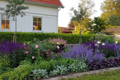 Bild på en liten vintage trädgård i full sol blomsterrabatt och framför huset på sommaren