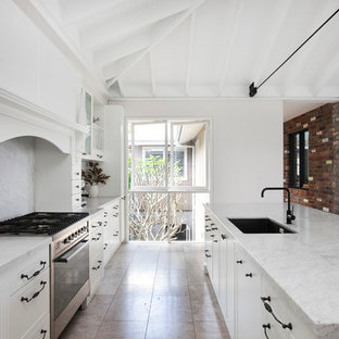 Kitchen pantry inspiration - Example of a galley limestone floor kitchen pantry design in Central Coast with a single-bowl sink, recessed-panel cabinets, white cabinets, marble countertops, gray backsplash, stone slab backsplash, stainless steel appliances and an island