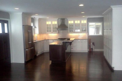 Inspiration for a galley dark wood floor open concept kitchen remodel in Detroit with an undermount sink, recessed-panel cabinets, white cabinets, granite countertops, white backsplash, subway tile backsplash, stainless steel appliances and an island