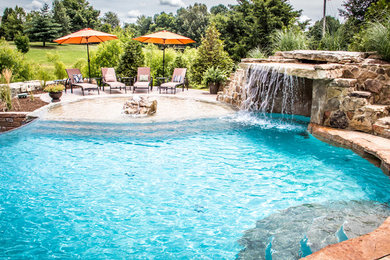 Inspiration for a large tropical backyard stamped concrete and custom-shaped natural pool fountain remodel in Chicago