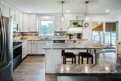 Inspiration for a transitional l-shaped porcelain tile open concept kitchen remodel in Baltimore with a double-bowl sink, shaker cabinets, white cabinets, granite countertops, beige backsplash, ceramic backsplash, stainless steel appliances, an island and beige countertops