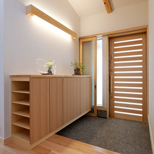 Idee per un piccolo corridoio etnico con pareti bianche, parquet chiaro, una porta scorrevole, una porta in legno chiaro e pavimento beige