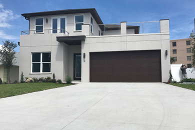 Inspiration for a mid-sized contemporary beige two-story stucco house exterior remodel in Orlando with a hip roof and a shingle roof