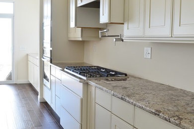 Example of a large u-shaped dark wood floor eat-in kitchen design in Detroit with beaded inset cabinets, white cabinets, granite countertops, stainless steel appliances and an island