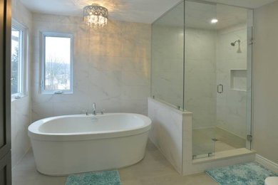 This is an example of a small midcentury master bathroom in Other with brown cabinets, a double vanity, a floating vanity, recessed-panel cabinets, a freestanding tub, a corner shower, a two-piece toilet, black and white tile, limestone, multi-coloured walls, limestone floors, an undermount sink, engineered quartz benchtops, beige floor, a hinged shower door, white benchtops and a niche.