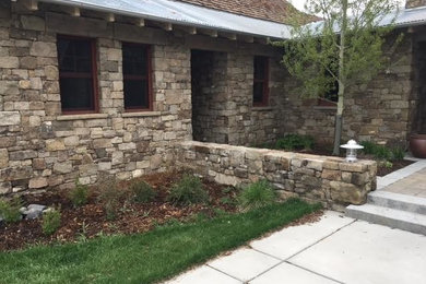Transitional brown stone house exterior idea in Other with a hip roof and a mixed material roof