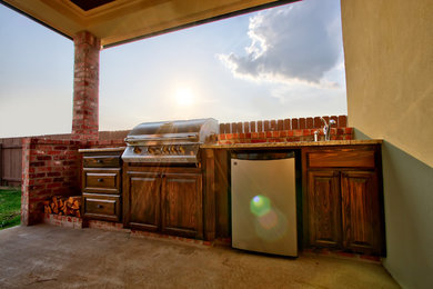 Elegant backyard concrete patio kitchen photo in New Orleans with a roof extension