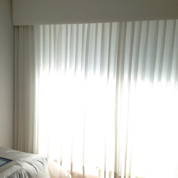 Bedroom with upholstered cornice with traversing sheer drapery