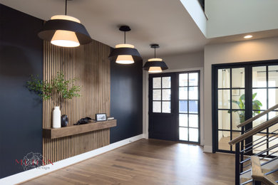 Example of a large medium tone wood floor and brown floor entryway design with multicolored walls and a glass front door