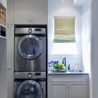 トロントの小さいトランジショナルスタイルのおしゃれな家事室 (ドロップインシンク、シェーカースタイル扉のキャビネット、グレーのキャビネット、ラミネートカウンター、白い壁、セラミックタイルの床、上下配置の洗濯機・乾燥機) の写真