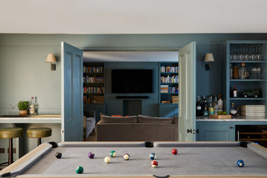 Hobbykeller ohne Kamin mit blauer Wandfarbe, braunem Holzboden, braunem Boden und Wandpaneelen in London