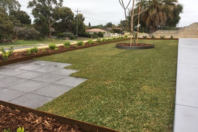 Photo of a mid-sized contemporary front yard full sun formal garden in Perth with mulch.