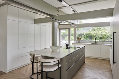 Contemporary kitchen in Surrey with flat-panel cabinets and an island.