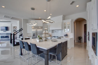 Design ideas for an expansive contemporary l-shaped eat-in kitchen in Houston with an integrated sink, glass-front cabinets, white cabinets, metallic splashback, porcelain splashback, stainless steel appliances, travertine floors and with island.