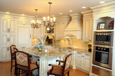 Mid-sized elegant l-shaped light wood floor kitchen photo in Other with an undermount sink, raised-panel cabinets, white cabinets, granite countertops, orange backsplash, porcelain backsplash, stainless steel appliances and an island