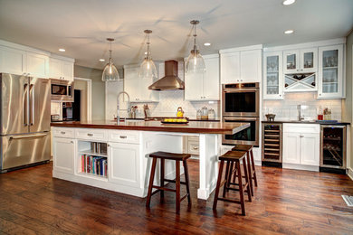 Photo of a traditional l-shaped kitchen in DC Metro with shaker cabinets, white cabinets, wood benchtops, white splashback, subway tile splashback, with island and brown benchtop.