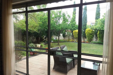 Photo of a mid-sized contemporary backyard patio in Miami with an awning and natural stone pavers.