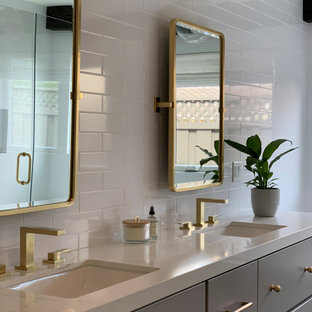 Inspiration för stora lantliga vitt en-suite badrum, med släta luckor, grå skåp, ett platsbyggt badkar, en dusch i en alkov, en toalettstol med hel cisternkåpa, vit kakel, keramikplattor, vita väggar, marmorgolv, ett undermonterad handfat, bänkskiva i kvarts, svart golv och dusch med gångjärnsdörr