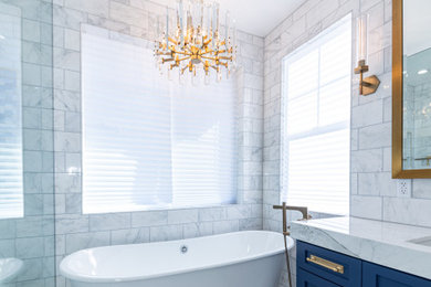 Large minimalist master white tile ceramic tile, white floor and double-sink tub/shower combo photo in Los Angeles with blue cabinets, white walls, marble countertops, a hinged shower door, white countertops and a built-in vanity