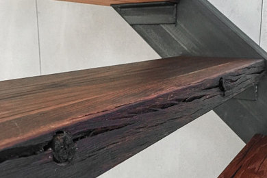 Ejemplo de escalera recta industrial grande con escalones de madera, barandilla de metal y ladrillo
