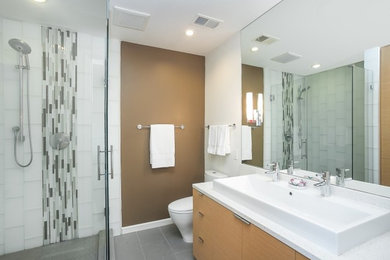 Corner shower - mid-sized contemporary kids' cement tile floor and gray floor corner shower idea in Santa Barbara with flat-panel cabinets, light wood cabinets, brown walls and a hinged shower door