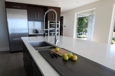 Inspiration for a large contemporary single-wall light wood floor and gray floor kitchen remodel in Vancouver with an undermount sink, flat-panel cabinets, medium tone wood cabinets, quartz countertops, white backsplash, marble backsplash, stainless steel appliances and an island