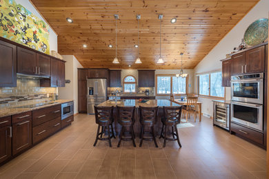 Elegant brown floor kitchen photo in Minneapolis with an undermount sink, shaker cabinets, dark wood cabinets, subway tile backsplash, stainless steel appliances, an island and multicolored countertops