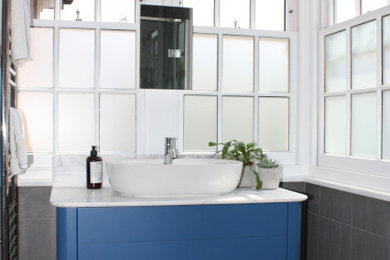 Photo of a small scandinavian grey and teal bathroom in London with flat-panel cabinets, blue cabinets, a walk-in shower, a wall mounted toilet, grey tiles, slate tiles, grey walls, slate flooring, a console sink, marble worktops, grey floors, a hinged door, white worktops, feature lighting, a single sink, a freestanding vanity unit and a coffered ceiling.