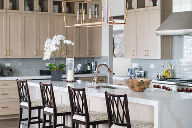 Inspiration for a large transitional u-shaped medium tone wood floor and brown floor kitchen remodel in Chicago with an undermount sink, shaker cabinets, beige cabinets, quartz countertops, glass tile backsplash, stainless steel appliances, an island and white countertops