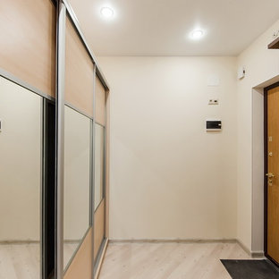 Esempio di un corridoio nordico di medie dimensioni con pareti beige, pavimento in laminato, una porta singola, una porta in legno bruno e pavimento beige