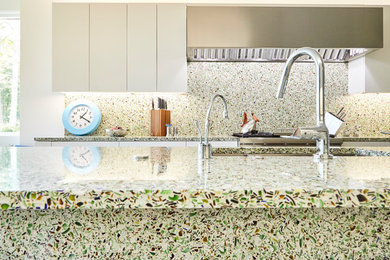 Enclosed kitchen - mid-sized contemporary galley slate floor and blue floor enclosed kitchen idea in New York with an undermount sink, flat-panel cabinets, white cabinets, recycled glass countertops, green backsplash, glass sheet backsplash, stainless steel appliances and an island