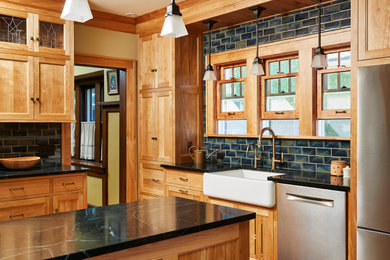 Large arts and crafts light wood floor eat-in kitchen photo in Minneapolis with a farmhouse sink, shaker cabinets, medium tone wood cabinets, soapstone countertops and green backsplash