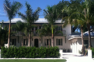 Large tropical white two-story stucco exterior home idea in Tampa with a gambrel roof