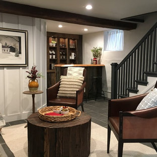 Photo of a medium sized rural walk-out basement in Philadelphia with white walls, a wood burning stove, a stone fireplace surround, grey floors and slate flooring.