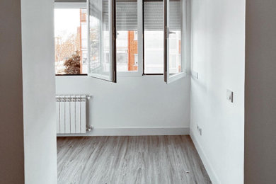 Modelo de salón cerrado y gris y blanco escandinavo grande de obra con paredes blancas, suelo de madera oscura, televisor colgado en la pared y suelo gris