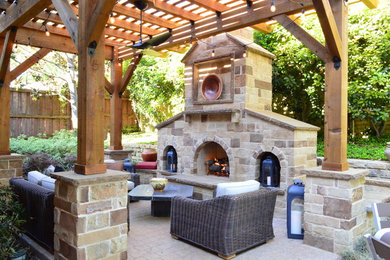 This is an example of a mid-sized mediterranean backyard patio in Dallas with a fire feature, natural stone pavers and a pergola.