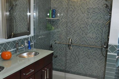 Mid-sized trendy master gray tile and ceramic tile mosaic tile floor alcove shower photo in Cincinnati with recessed-panel cabinets, dark wood cabinets, a one-piece toilet, white walls, an undermount sink and glass countertops