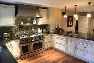 Elegant u-shaped medium tone wood floor eat-in kitchen photo in New York with a double-bowl sink, beaded inset cabinets, white cabinets, granite countertops, mosaic tile backsplash, stainless steel appliances, no island and multicolored backsplash